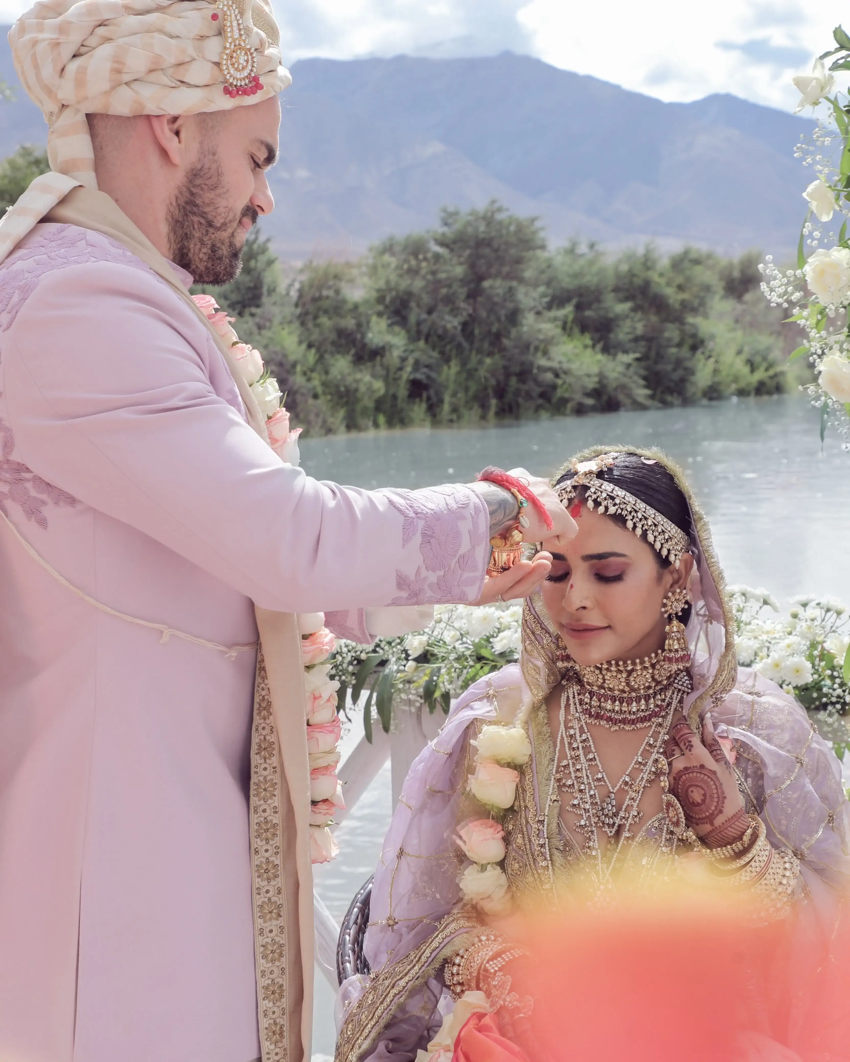 Groom applying sindoor during the lakeside mountain ceremony